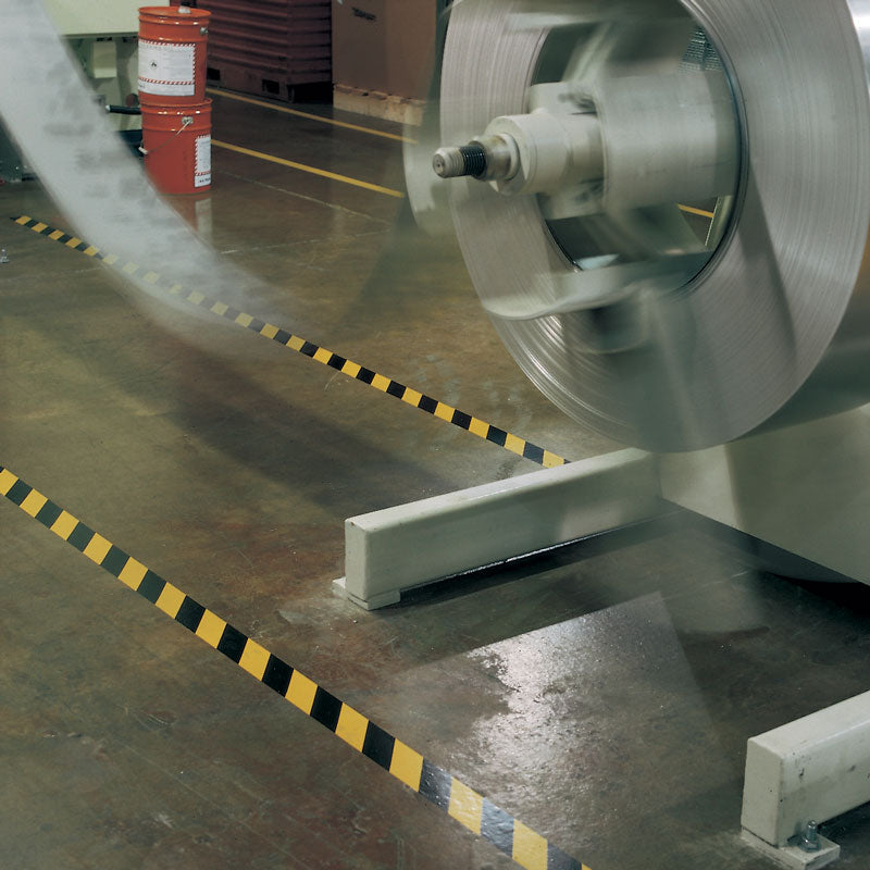 LWT210 Yellow/Black Laminated Adhesive Hazard Stripe Marking Tape (54 ft) on floor around moving machinery