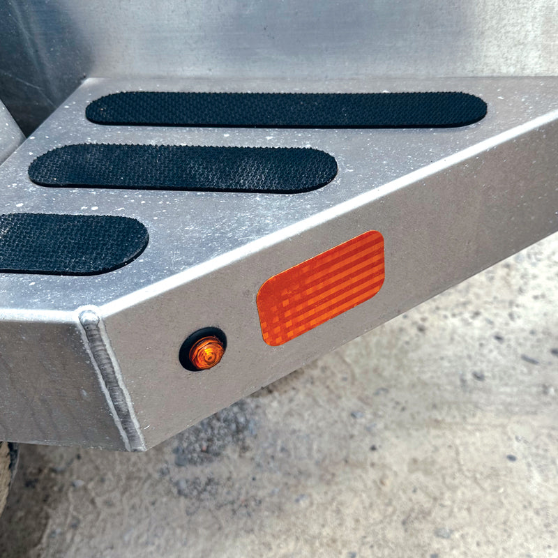 RR250AM RR2510AM Amber SAE A DOT Die Cut Adhesive Reflex Reflectors (2 in x 3.5 in) applied to a trailer step