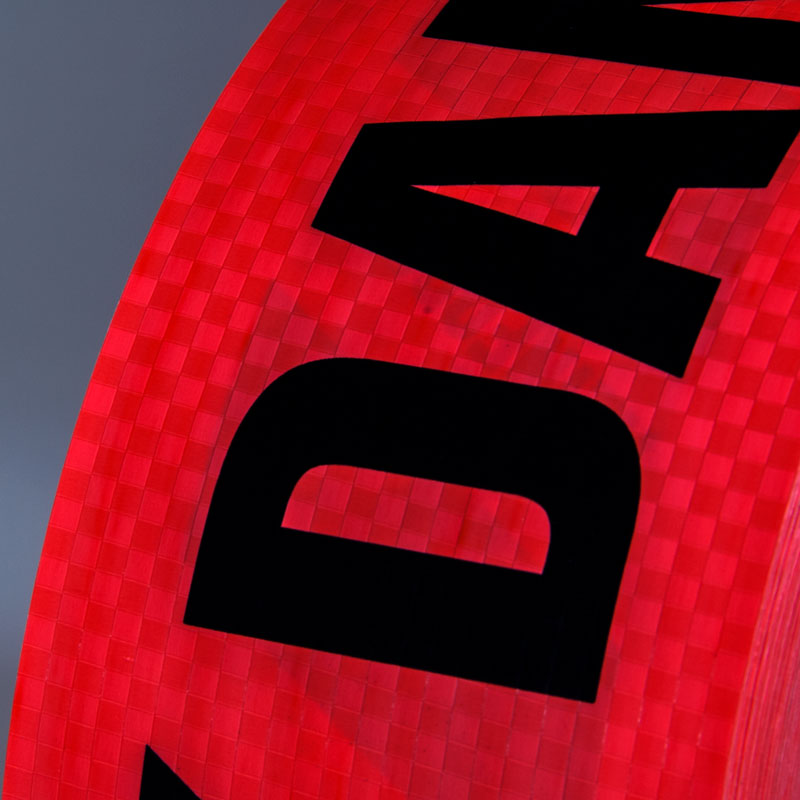 REBT2057 DANGER Reinforced Ultra-Durable Barricade Message Safety Tape (3 in x 500 ft) 12 /case close up of material